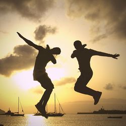 Silhouette man jumping on sea against sky during sunset