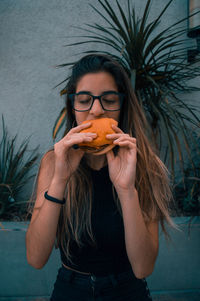 Portrait of young woman holding eyeglasses