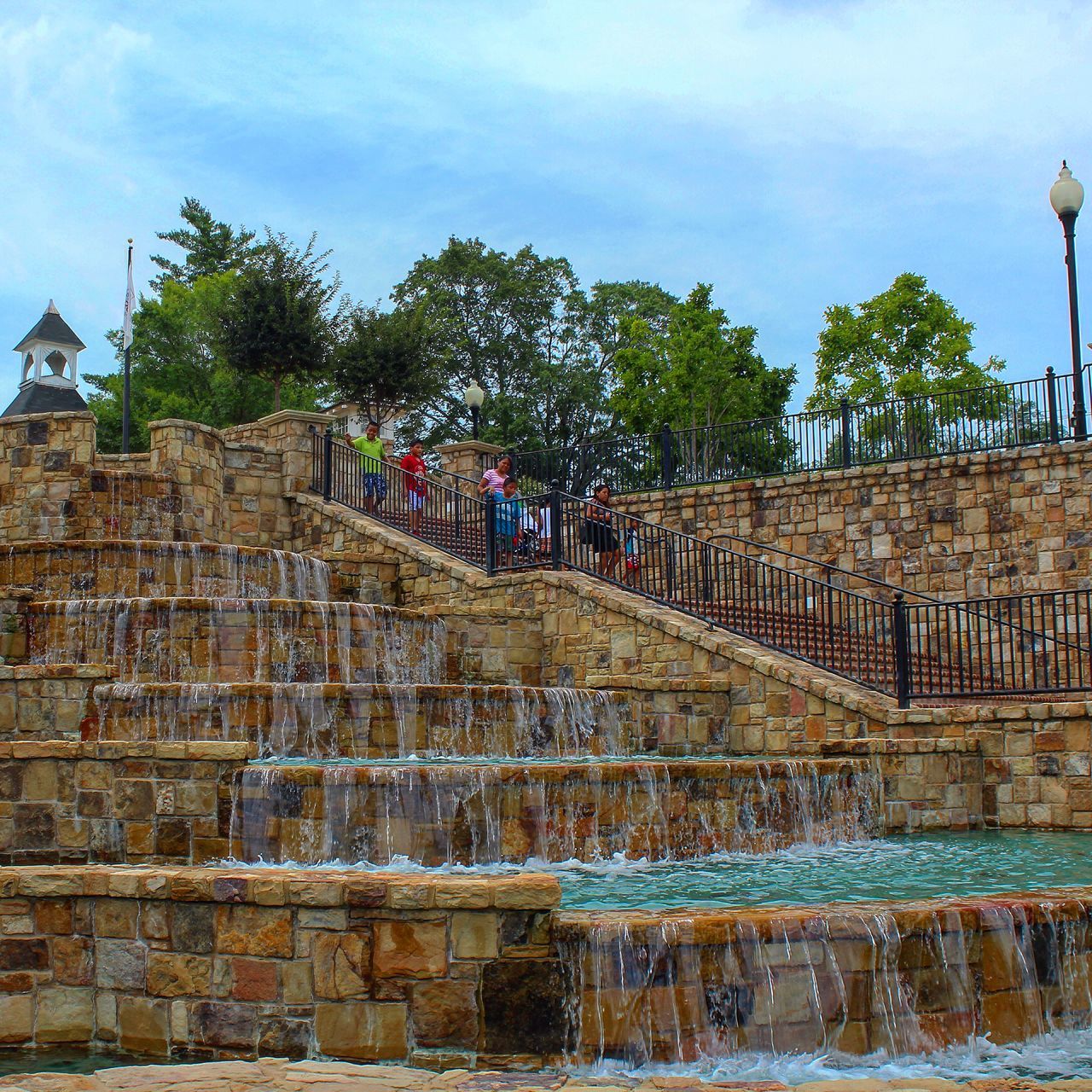 built structure, architecture, building exterior, tree, sky, water, day, outdoors, incidental people, wall - building feature, nature, cloud - sky, steps, large group of people, railing, stone wall, house, rock - object, person