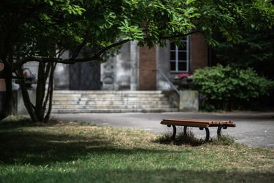 Empty bench in park against building