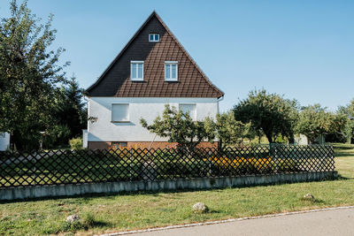 House and trees by building against sky