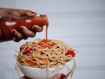 Close-up of person holding fast food spaghetti with hot sauce 