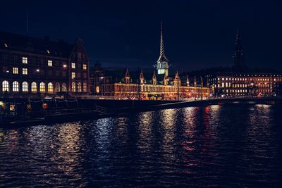 Illuminated buildings by river at night