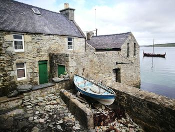 Old building by canal against sky