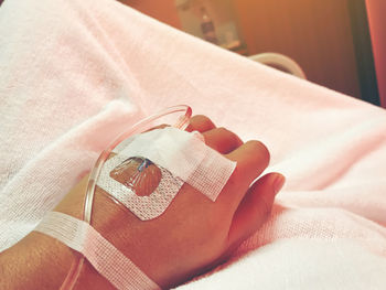 Close-up of human hand on bed