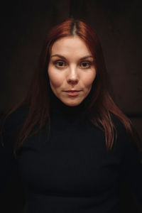 Portrait of young woman against black background