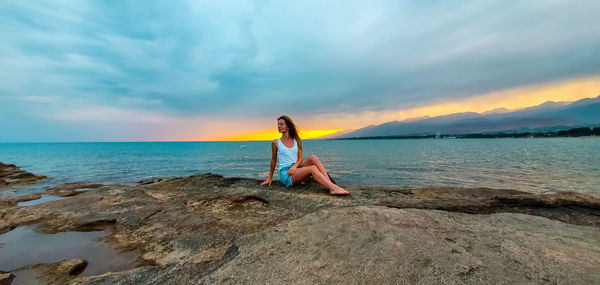 Full length of man on rock in sea against sky