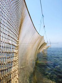 Close-up of fishing net at sea against clear blue sky