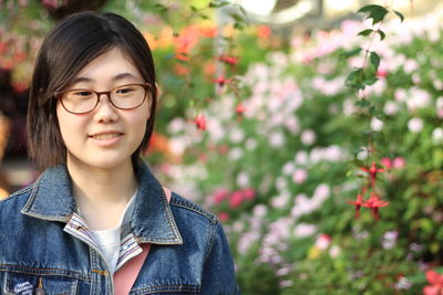 Portrait of woman with red eyes standing against plants