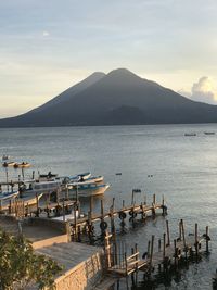 Scenic view of lake atitlan facing volcanoa against sky during sunset