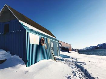 Snow covered building against blue sky