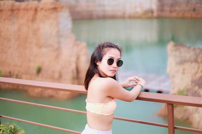 Portrait of young woman in sunglasses against railing