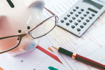 High angle view of piggy bank and office supplies