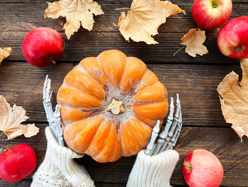 Skeleton hands holding a ripe orange pumpkin