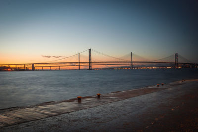 View of suspension bridge in city at sunset