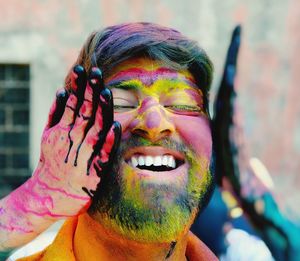 Cropped hand of person applying powder paint on smiling man face