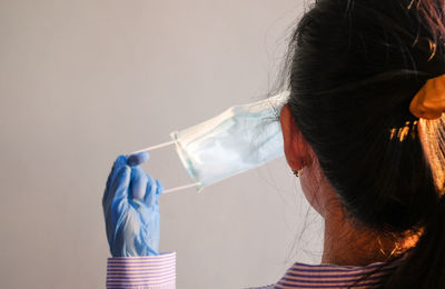 Rear view of woman holding face mask against corona virus