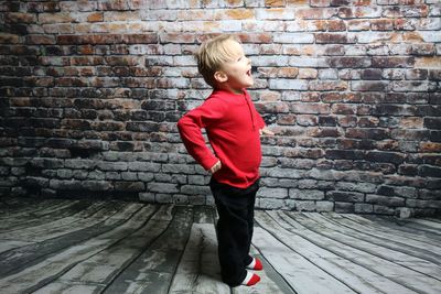 Full length of boy standing against brick wall