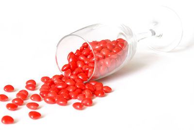 High angle view of red berries on white background