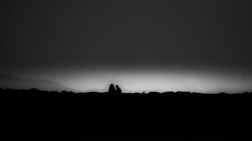 Silhouette people on field against clear sky