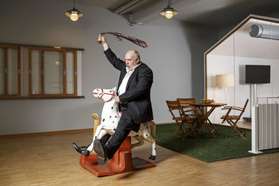 Businessman on rocking horse pretending to ride