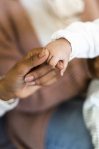 Baby holding woman's hand