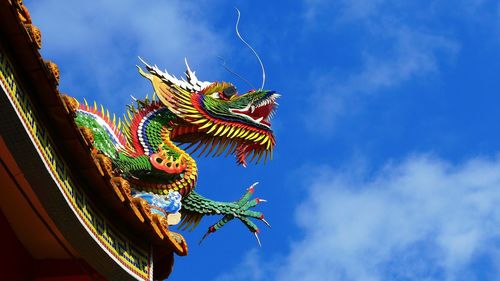 Low angle view of chinese dragon on roof against blue sky