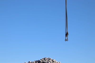 Low angle view of hanging chain  against clear blue sky