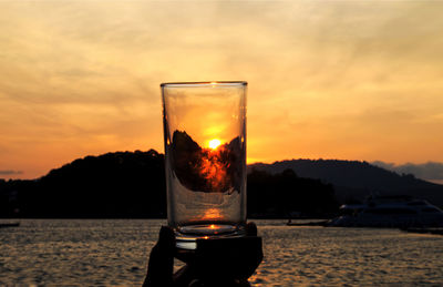 Close-up of beer glass against orange sky