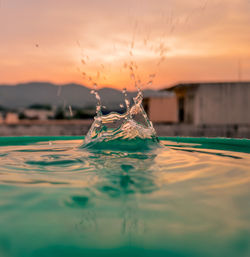 Close-up of water splashing in sea against sky during sunset