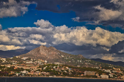 View of townscape by mountain against cloudy sky