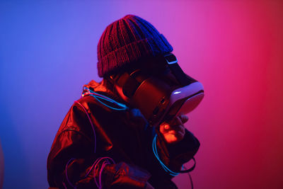 Fashionable boy child in a silver jacket and blue hat and glasses virtual reality playing a game