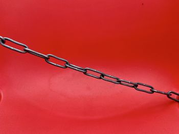 Close-up of chain against red background