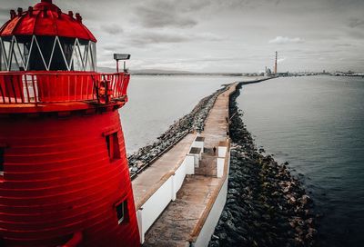 Red pier over sea against sky