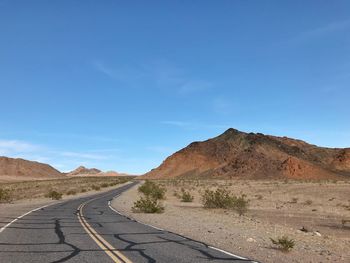 Road leading towards mountain against sky