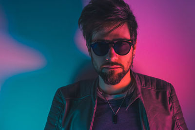 Portrait of young man wearing sunglasses against gray background