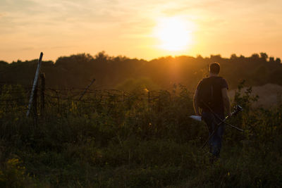 Man on field against sky during sunset