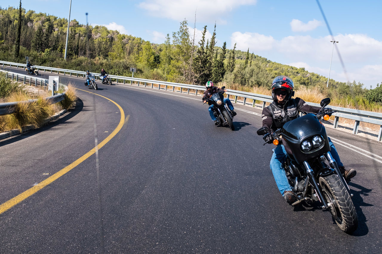 road, transportation, motorcycle, helmet, mode of transportation, sign, land vehicle, sports helmet, headwear, real people, group of people, day, nature, riding, symbol, full length, motion, men, sky, biker, crash helmet