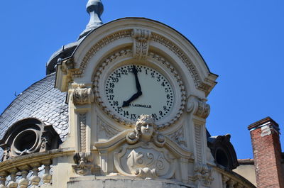 Low angle view of clock on building against sky