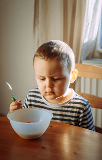 Close-up of cute boy eating cornflakes at home