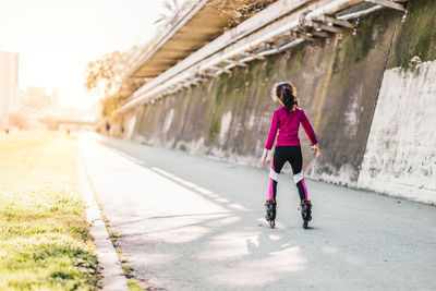 Rear view of girl inline skating on road