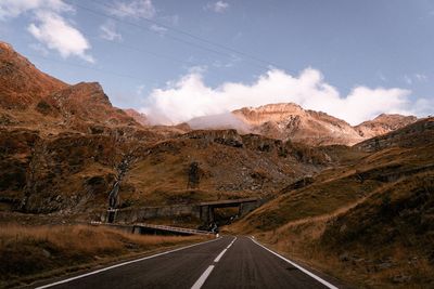 Road leading towards mountains against sky