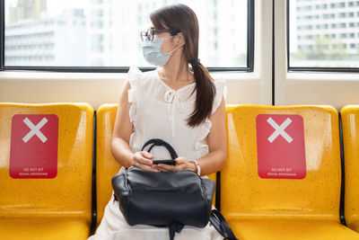 Woman using mobile phone while sitting in bus