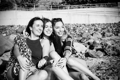 Smiling friends sitting at beach