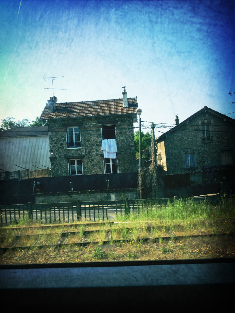 building exterior, architecture, built structure, blue, house, clear sky, sky, copy space, residential structure, no people, outdoors, field, residential building, day, road, building, railroad track, grass, window, tree