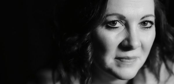 Close-up portrait of woman against black background