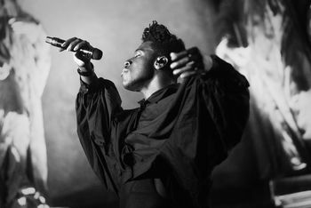 FULL LENGTH OF MAN WITH ARMS RAISED STANDING ON STAGE