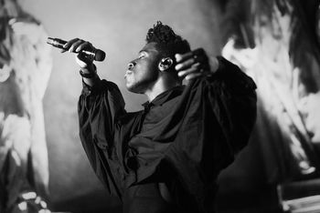 FULL LENGTH OF MAN WITH ARMS RAISED STANDING ON STAGE