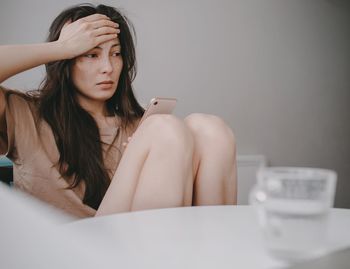 Portrait of young sad woman sitting on table