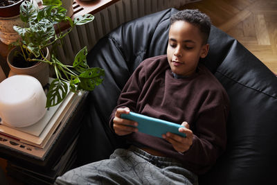 Boy lying on bean bag and playing video games